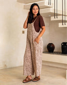 Woman wearing a patterned jumpsuit standing in a modern indoor setting.