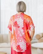 Person wearing a colorful kimono-style garment in a room with white walls and furniture.