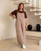 Woman wearing a brown and white patterned jumpsuit in a modern indoor setting.