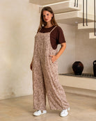 Woman wearing a patterned jumpsuit standing in a modern interior setting.