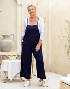 Woman wearing a navy jumpsuit with a white cardigan in a home setting