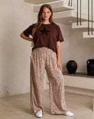 Woman wearing a brown t-shirt with a star design and leopard print pants in an indoor setting.