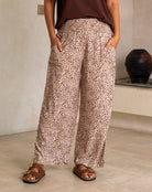 Person wearing leopard print pants and brown sandals in a minimal indoor setting.