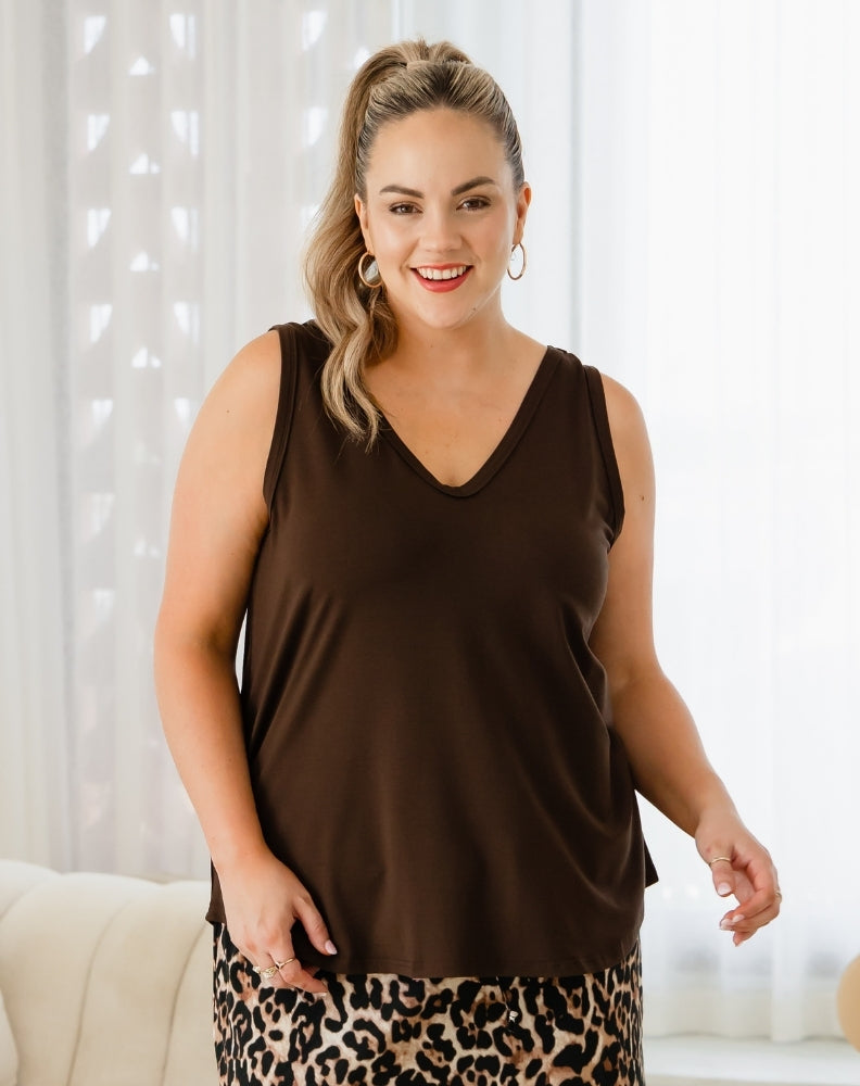 Woman wearing a brown sleeveless top with a leopard print skirt against a white curtain background
