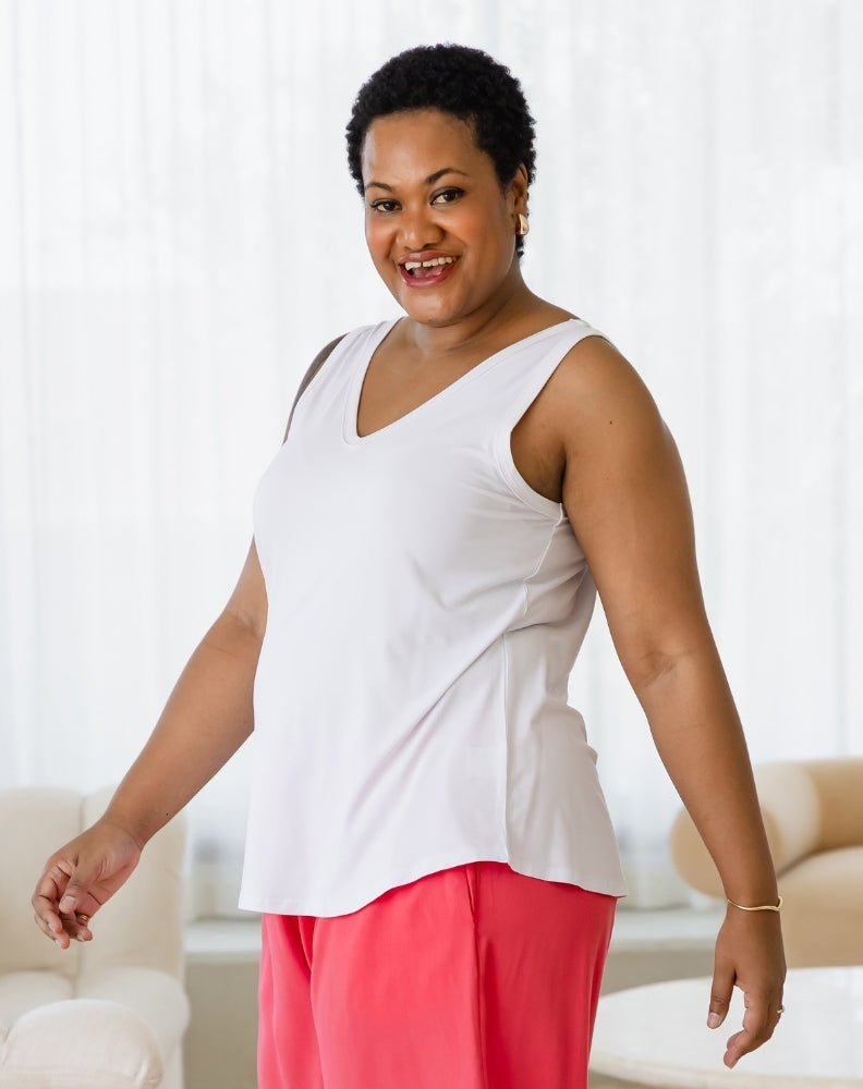 Woman wearing a white top and pink pants in a bright room