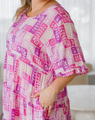 Person wearing a pink and purple patterned dress with a blurred background