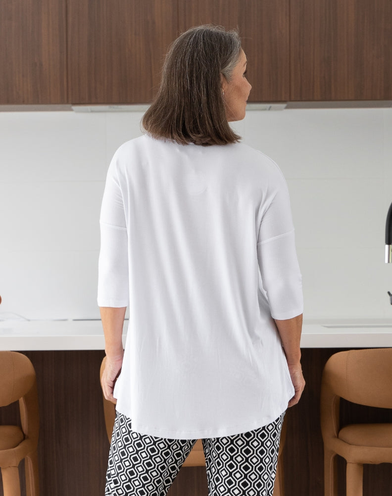 Person wearing a white top and patterned pants in a kitchen setting