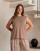 Woman wearing a brown sleeveless top and leopard print pants standing in a room with a staircase.