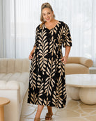 Woman wearing a black and beige patterned dress in a living room setting