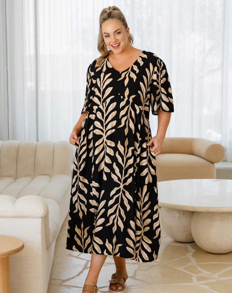 Woman wearing a black and beige patterned dress in a living room setting