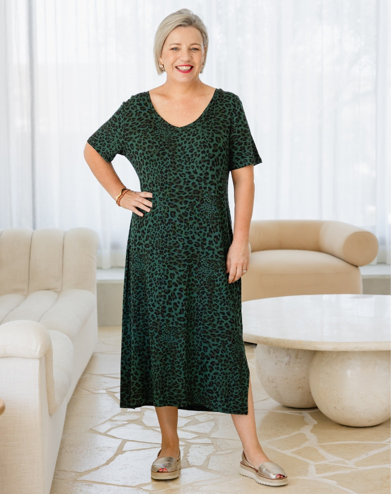 Woman wearing a green dress with a leopard print pattern in a living room setting.
