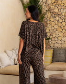 Woman wearing a leopard print outfit standing in a living room with a stone wall background.