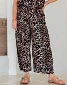 Person wearing leopard print pants with a neutral background