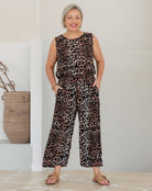 Woman wearing a leopard print jumpsuit standing against a plain background