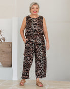 Woman wearing a leopard print jumpsuit standing indoors with a neutral background