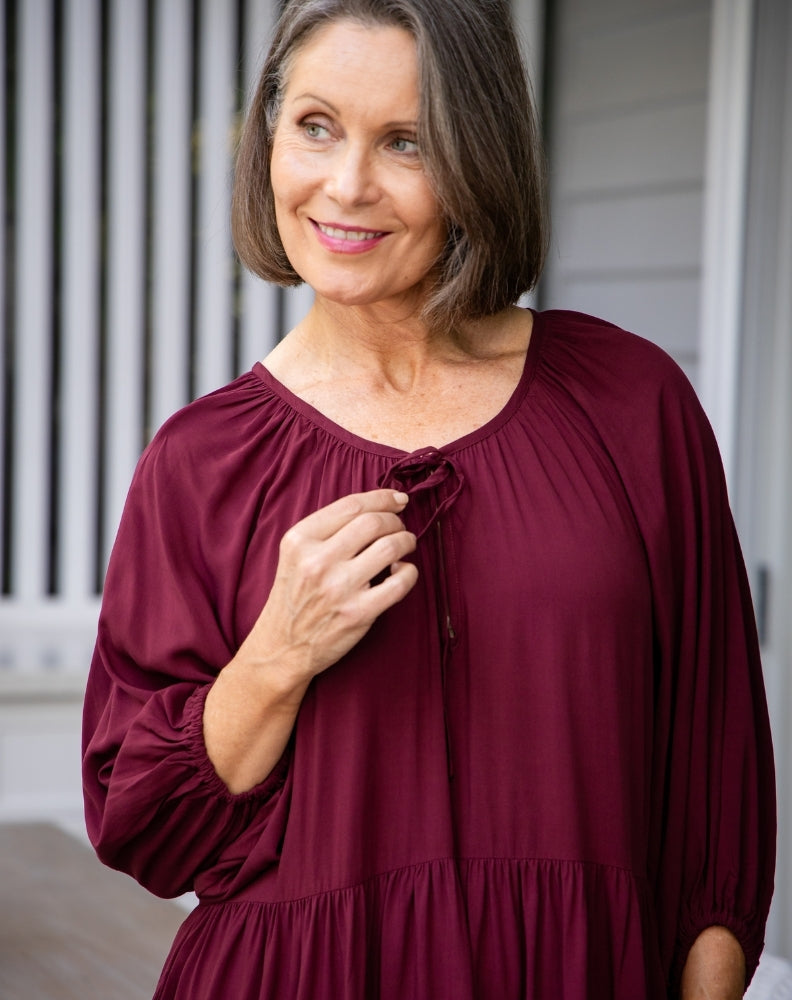 Woman wearing a burgundy dress standing outdoors.
