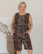 Woman wearing a leopard print jumpsuit standing against a plain background