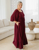 Woman in a burgundy dress standing in a living room.