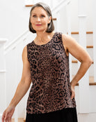Woman wearing a leopard print sleeveless top in a home setting.