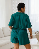 Woman wearing a teal romper in a living room setting