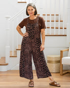 Woman wearing a leopard print jumpsuit and brown shirt indoors.