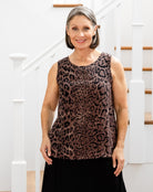 Woman wearing a leopard print sleeveless top standing in front of a staircase.