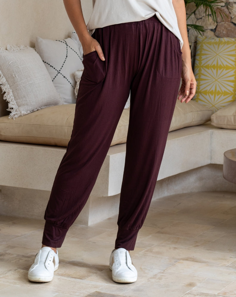 Person wearing maroon pants and white sneakers in a living room setting