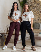 Two women wearing matching outfits with a cross symbol in a living room setting.