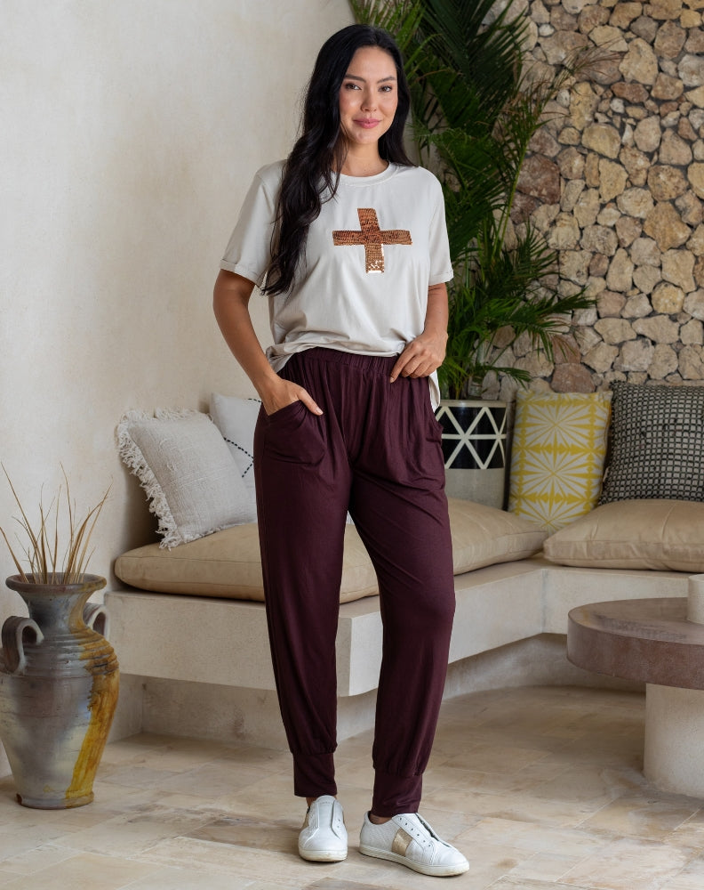 Woman in a casual outfit standing in a living room with a stone wall and sofa.