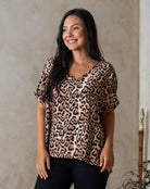 Woman wearing a leopard print top against a neutral background