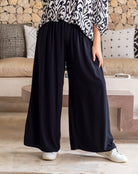 Person wearing black wide-leg pants and a patterned top in a living room setting.