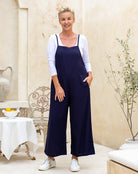 Woman wearing navy blue overalls in a home setting