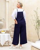 Woman wearing navy blue overalls in a home setting