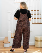 Person wearing leopard print overalls and a black top in a home setting.