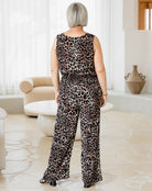 Person wearing a leopard print jumpsuit in a room with white walls and a beige armchair.
