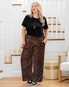 Woman wearing a black t-shirt and leopard print pants standing in a home setting.