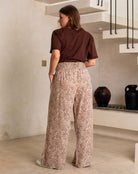 Woman wearing a brown top and leopard print pants in a room with a staircase.