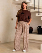 Woman wearing a brown t-shirt and leopard print pants in an indoor setting.