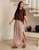 Woman wearing a brown top and patterned skirt in a home setting