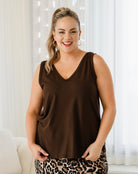 Woman wearing a brown sleeveless top with a leopard print skirt against a white curtain background