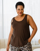 Woman wearing a brown sleeveless top and leopard print pants indoors.