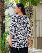 Woman wearing a black and white patterned top.