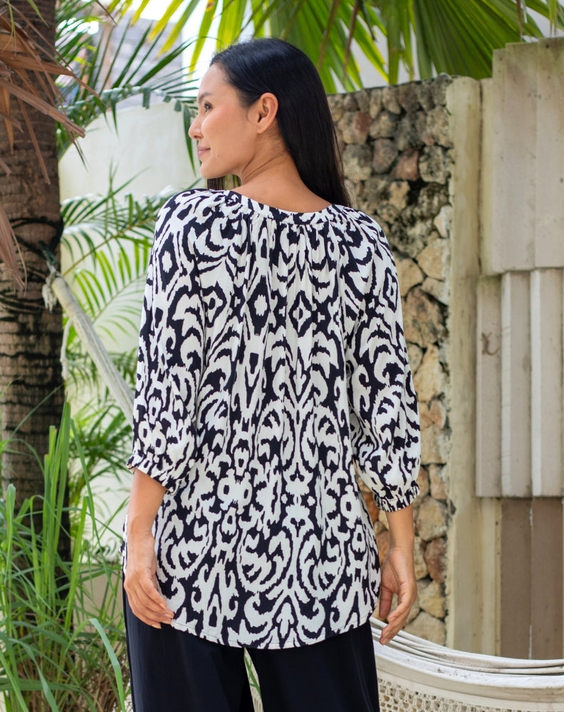 Woman wearing a black and white patterned top.