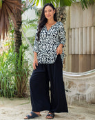 Woman wearing a black and white patterned top and black pants.