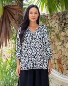 Woman wearing a black and white patterned blouse.