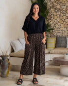Woman wearing a black shirt and leopard print pants in a living room setting.