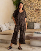 Woman wearing a leopard print outfit standing in a living room.