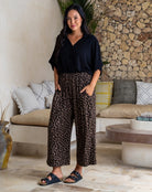Woman wearing a black top and leopard print pants in a living room setting.