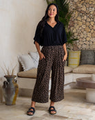 Woman wearing a black shirt and leopard print pants standing in a living room.