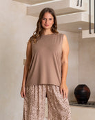 Woman wearing a sleeveless brown top and leopard print pants in an indoor setting.